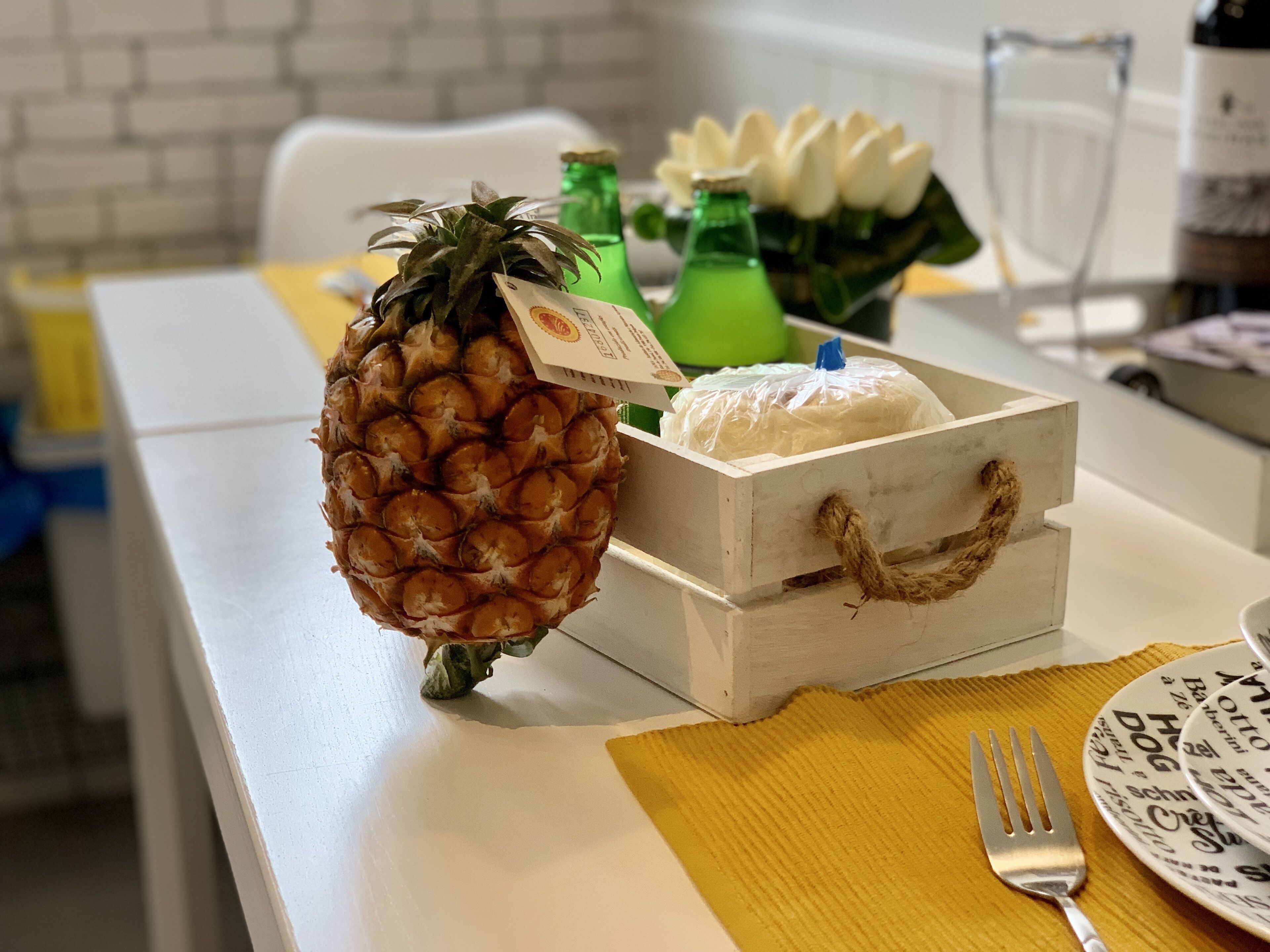 Un ananas sur une table, à côté d’une boîte blanche et d’une fourchette.