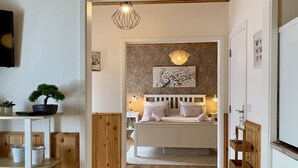 A bedroom with a bed, bedside tables, a lamp, a wall-mounted artwork, and a hanging light fixture. - Villaverde Azores (Ponta Delgada)