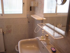 A bathroom with a sink, mirror, and a shelf with toiletries. - Ref. Alm03 -  (Rosas / Roses)