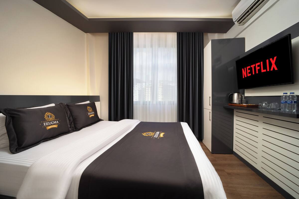 Une chambre d’hôtel équipée d’un lit, d’une télévision à écran plat, d’un minibar et offrant une vue sur la ville.
