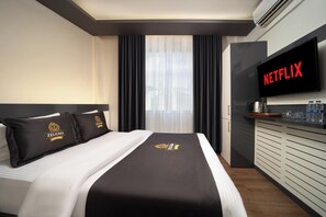 Habitación de hotel con cama, televisión de pantalla plana, minibar y vistas a la ciudad.