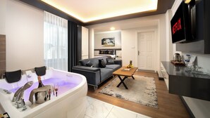 A modern living room with a large white bathtub, a grey sofa, a wooden coffee table, and a flat-screen TV mounted on the wall. - Bakırköy Zeugma Suit  (Istanbul)