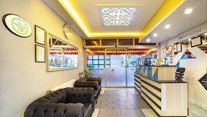 A reception area with a reception desk, a waiting area with cushioned seating, framed certificates on the wall, and a patterned rug. - Bakırköy Zeugma Suit  (Istanbul)