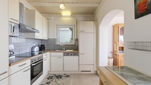 A kitchen with white cabinets, a stove, a sink, and a window.