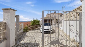 A gated driveway leading to a house with a white car parked inside.