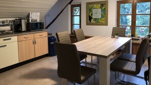 Une cuisine équipée d’une table et de chaises, d’un four à micro-ondes, d’une machine à café et d’un escalier.