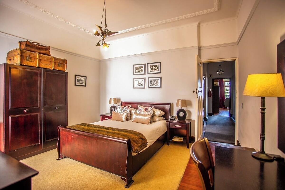 Une chambre à coucher avec un lit en bois, une armoire, un bureau et une lampe.