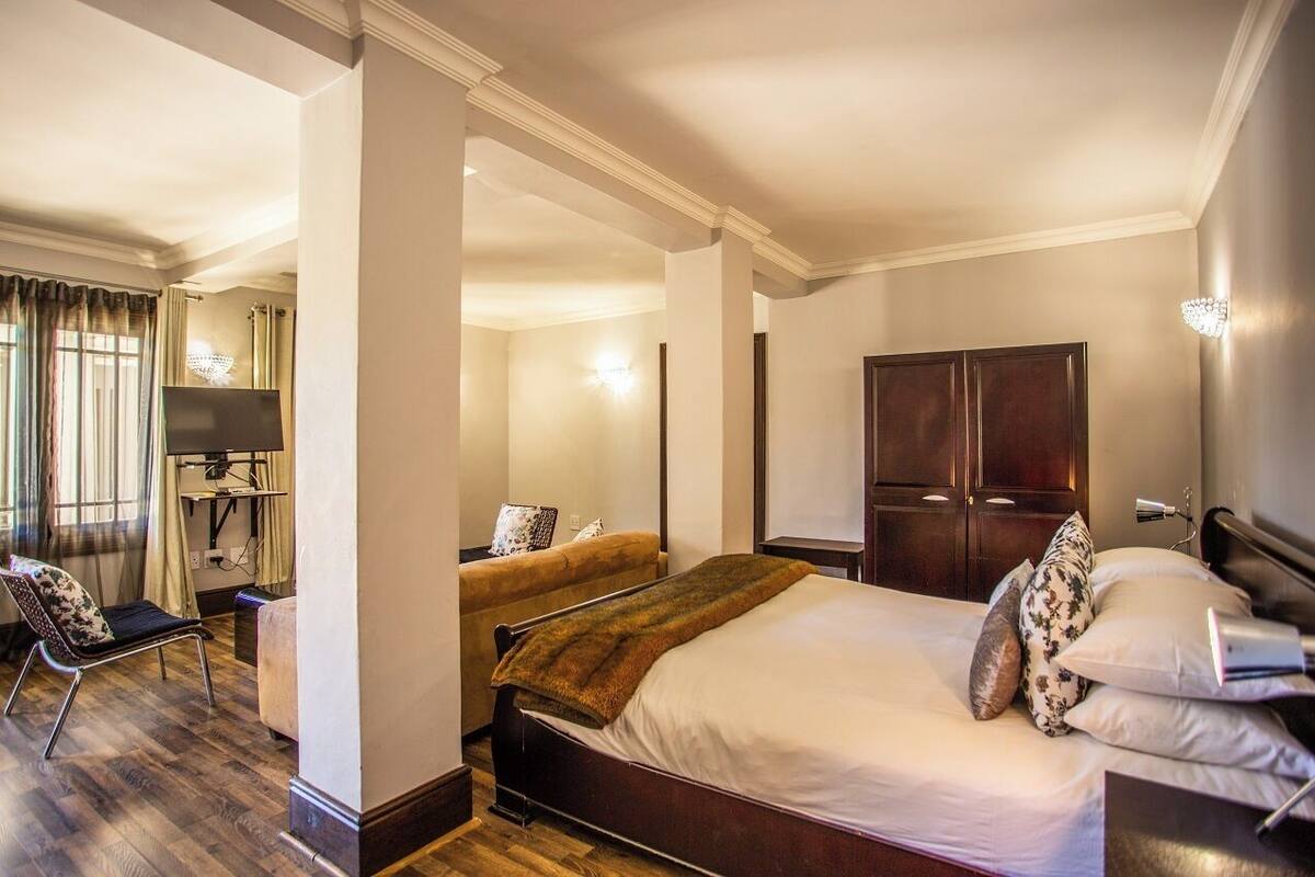 Une chambre d’hôtel comprenant un lit, une chaise, un bureau avec un ordinateur et une armoire.