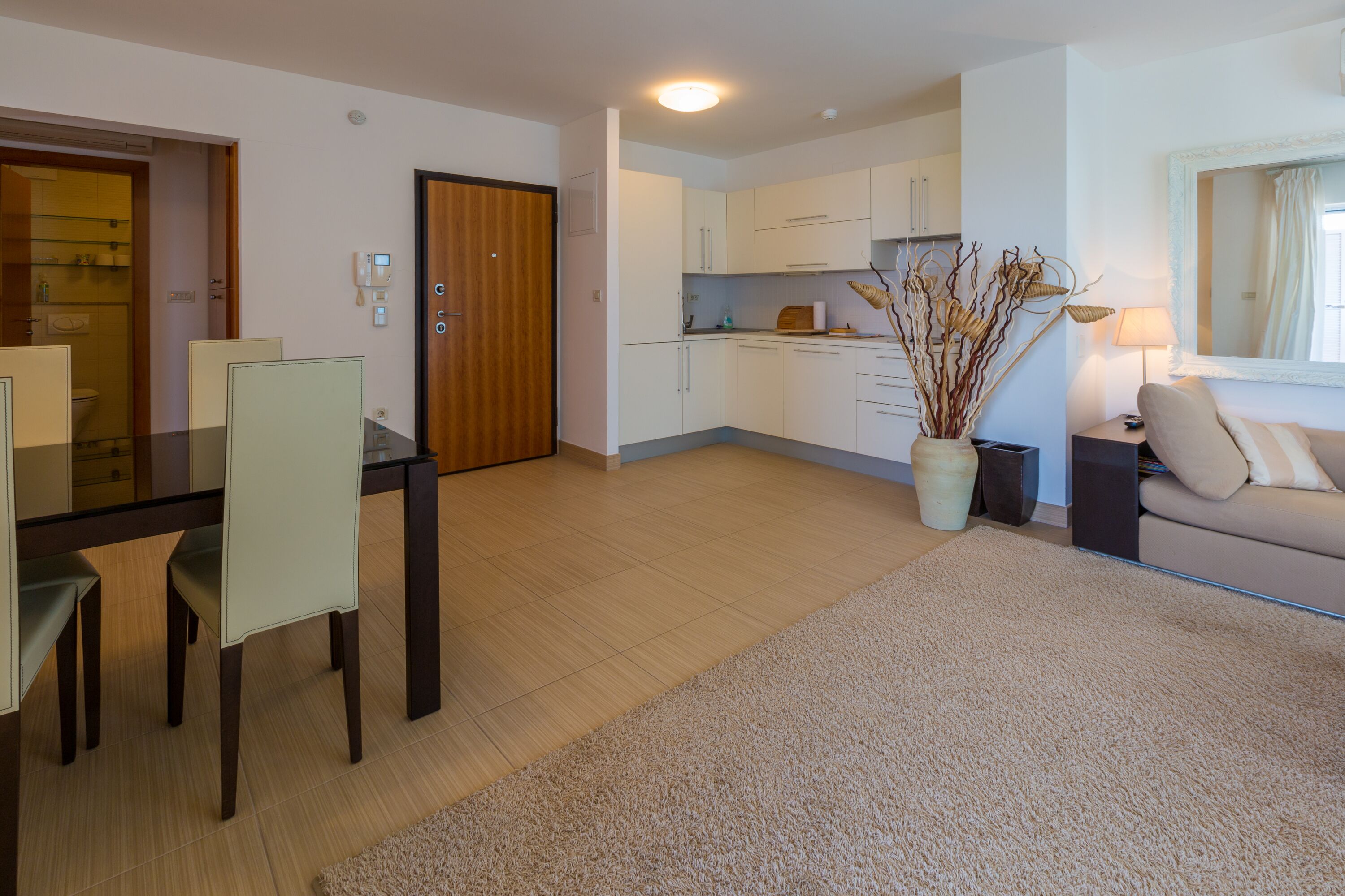 A modern living room with a dining area, a kitchen, and a bathroom.
