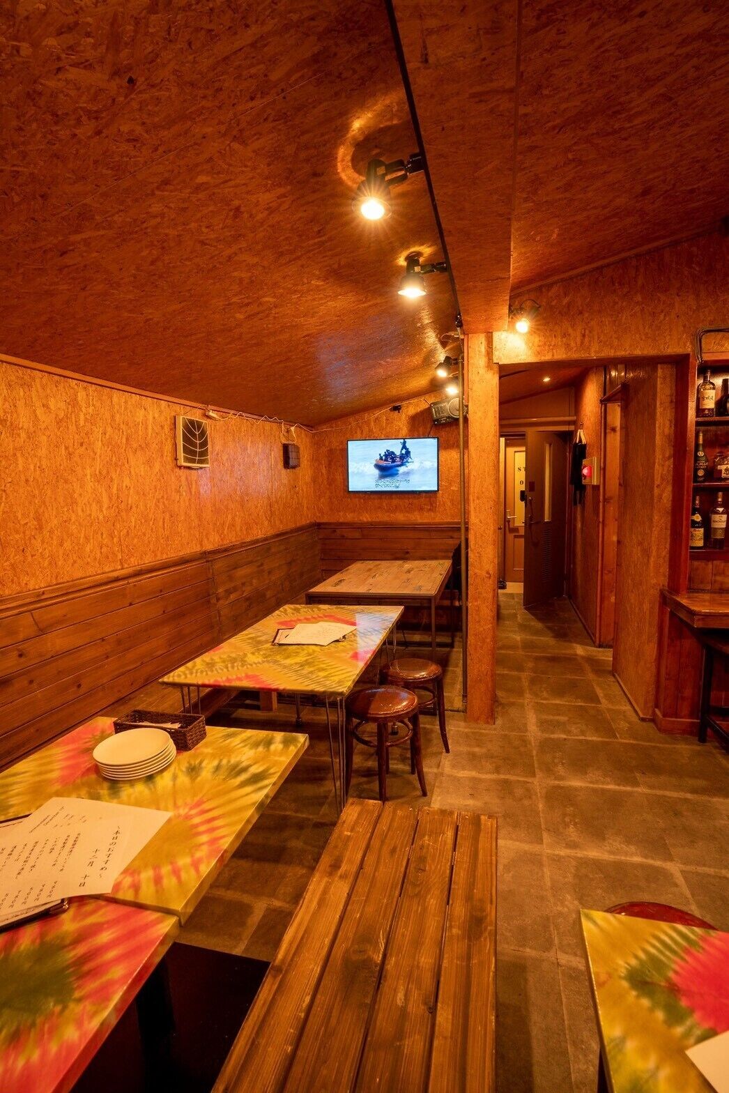 A restaurant with wooden walls and tables, a television screen, and a bar area.