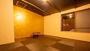 A room with tatami mat flooring, a futon bed, a small exercise equipment, and a window with a view. - Youtei - Hostel (Rusutsu)