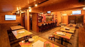 A cozy restaurant with wooden walls and ceiling, bar area, and multiple tables and chairs. - Youtei - Hostel (Rusutsu)