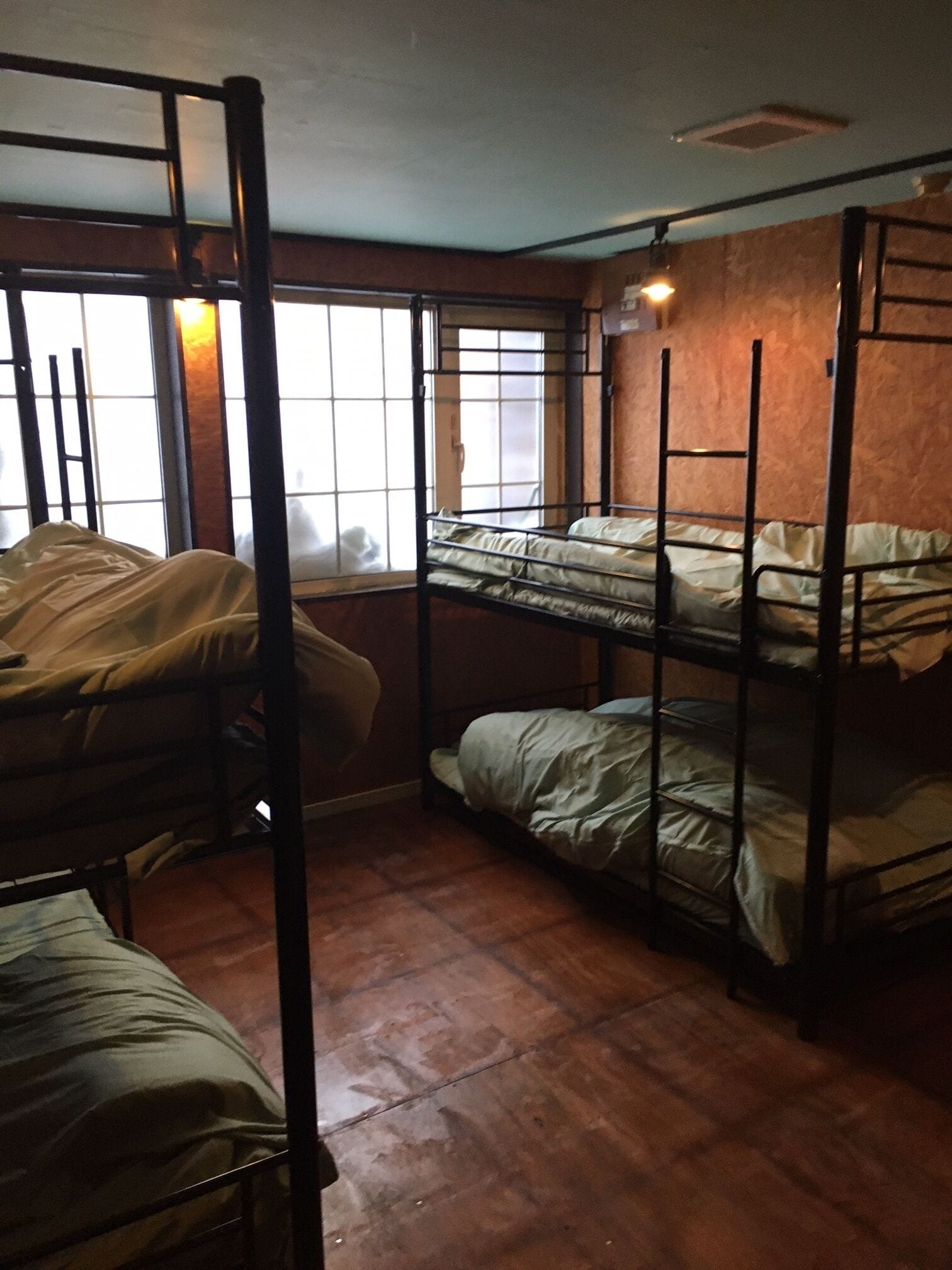 A dormitory room with bunk beds, a window with a view, and a radiator.
