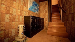 A hallway with patterned wallpaper, a large blue artwork, a vintage radio, and a staircase leading to another floor. - Youtei - Hostel (Rusutsu)