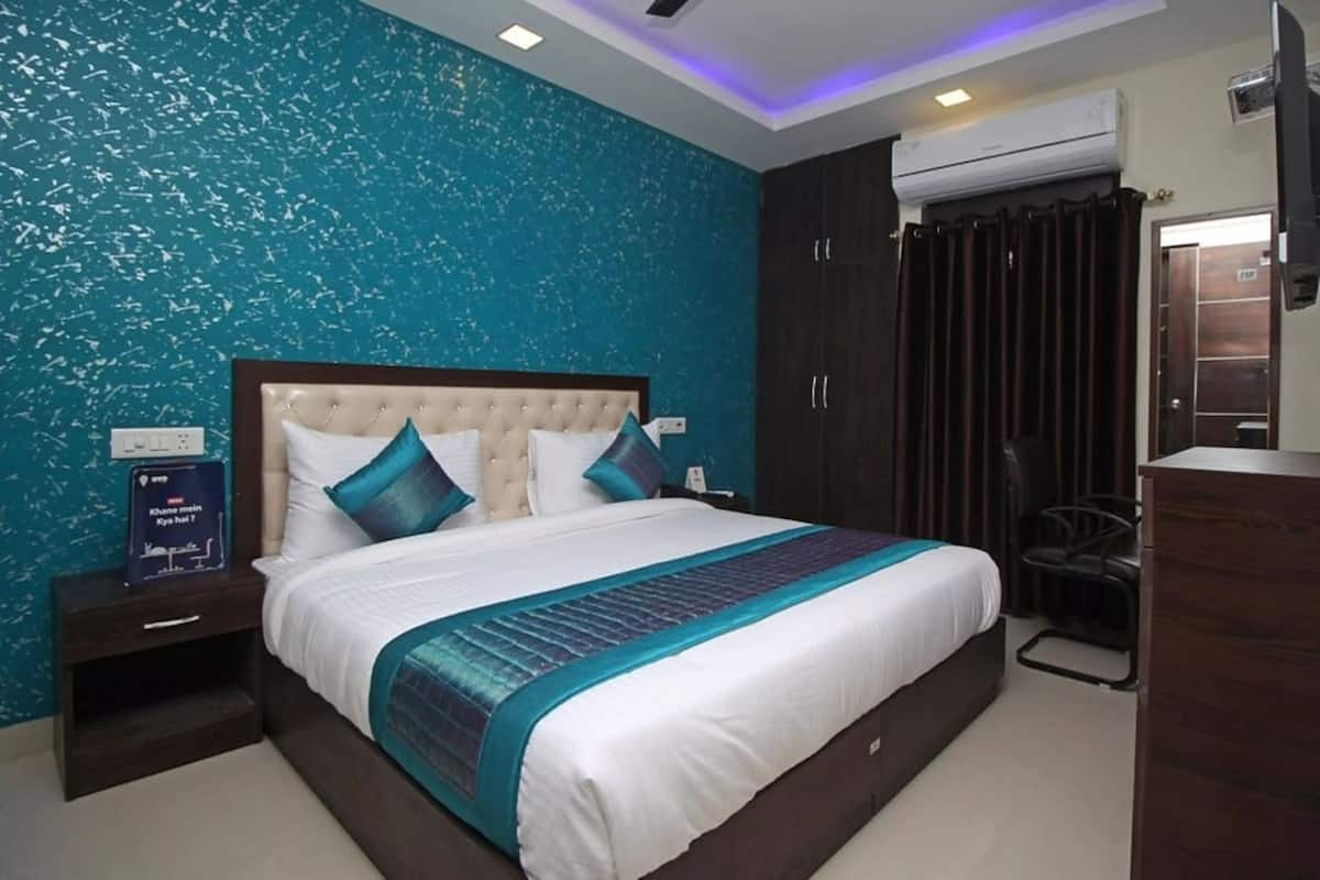 A modern bedroom with a large bed, dark wooden wardrobe, and a teal textured wall.