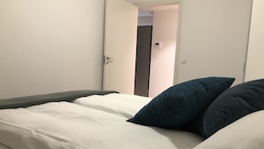 A single bed with white bedding and two dark blue pillows. - The Meridian (Tromsø)