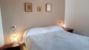 Une chambre à coucher comprenant un lit, deux tables de chevet et trois cadres photo accrochés au mur.