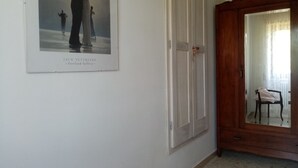 Un couloir avec un tableau encadré représentant un couple, une armoire en bois et une chaise.