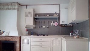 Une cuisine compacte dotée d’une cuisinière à gaz, de meubles blancs et d’un dosseret carrelé.