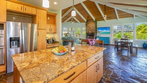 A spacious kitchen with granite countertops, wooden cabinets, and a stainless steel refrigerator.