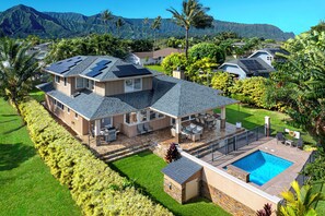 A large house with a swimming pool, solar panels, and a well-maintained garden. - Pohaku Villa: Gorgeous Home w/AC, Pool, Relaxing Lanai Area & Garden Views (Princeville)
