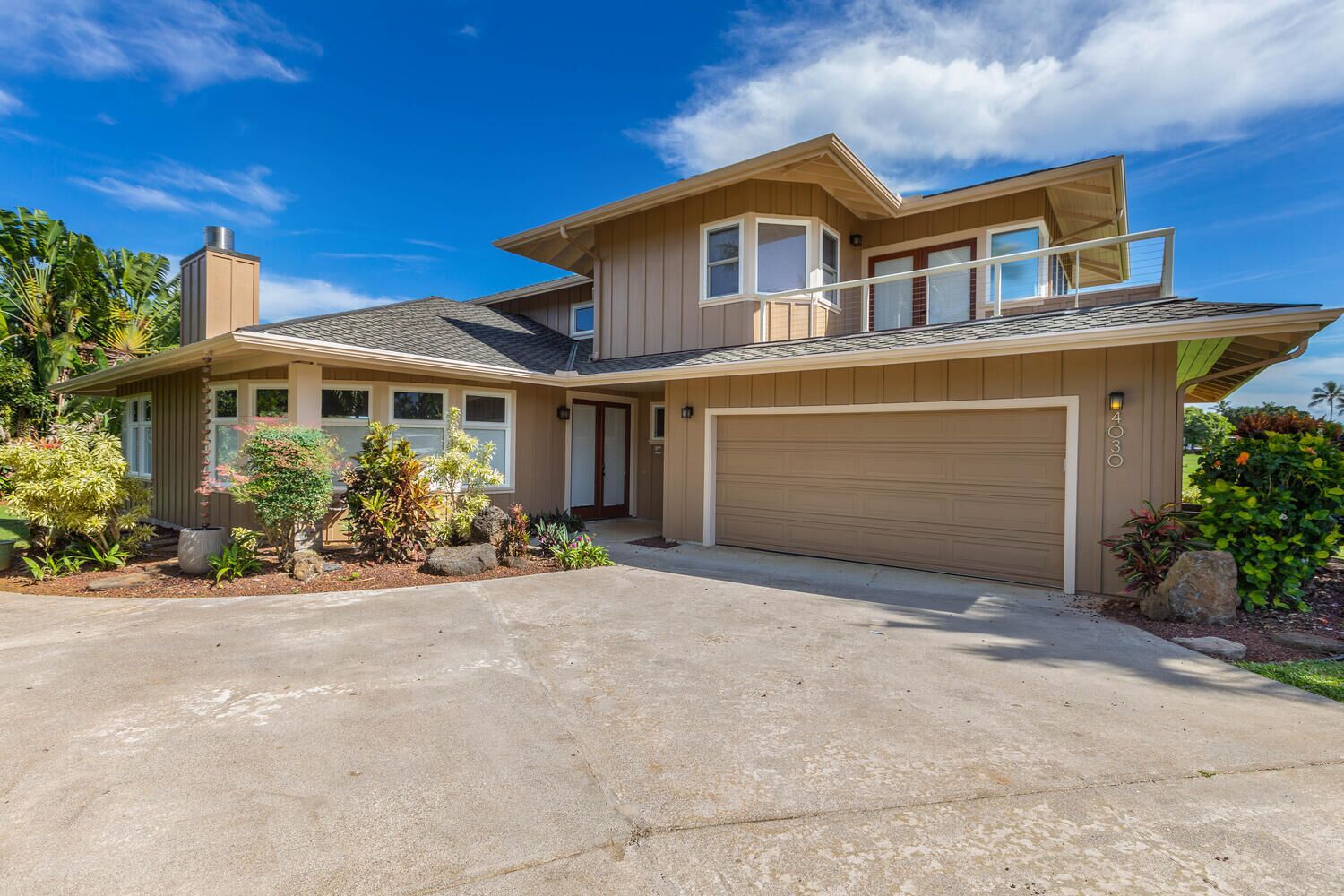 A two-story house with a garage, a covered porch, and a landscaped front yard.