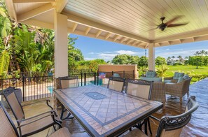 A covered outdoor patio with a pool table, chairs, and a ceiling fan. - Pohaku Villa: Gorgeous Home w/AC, Pool, Relaxing Lanai Area & Garden Views (Princeville)