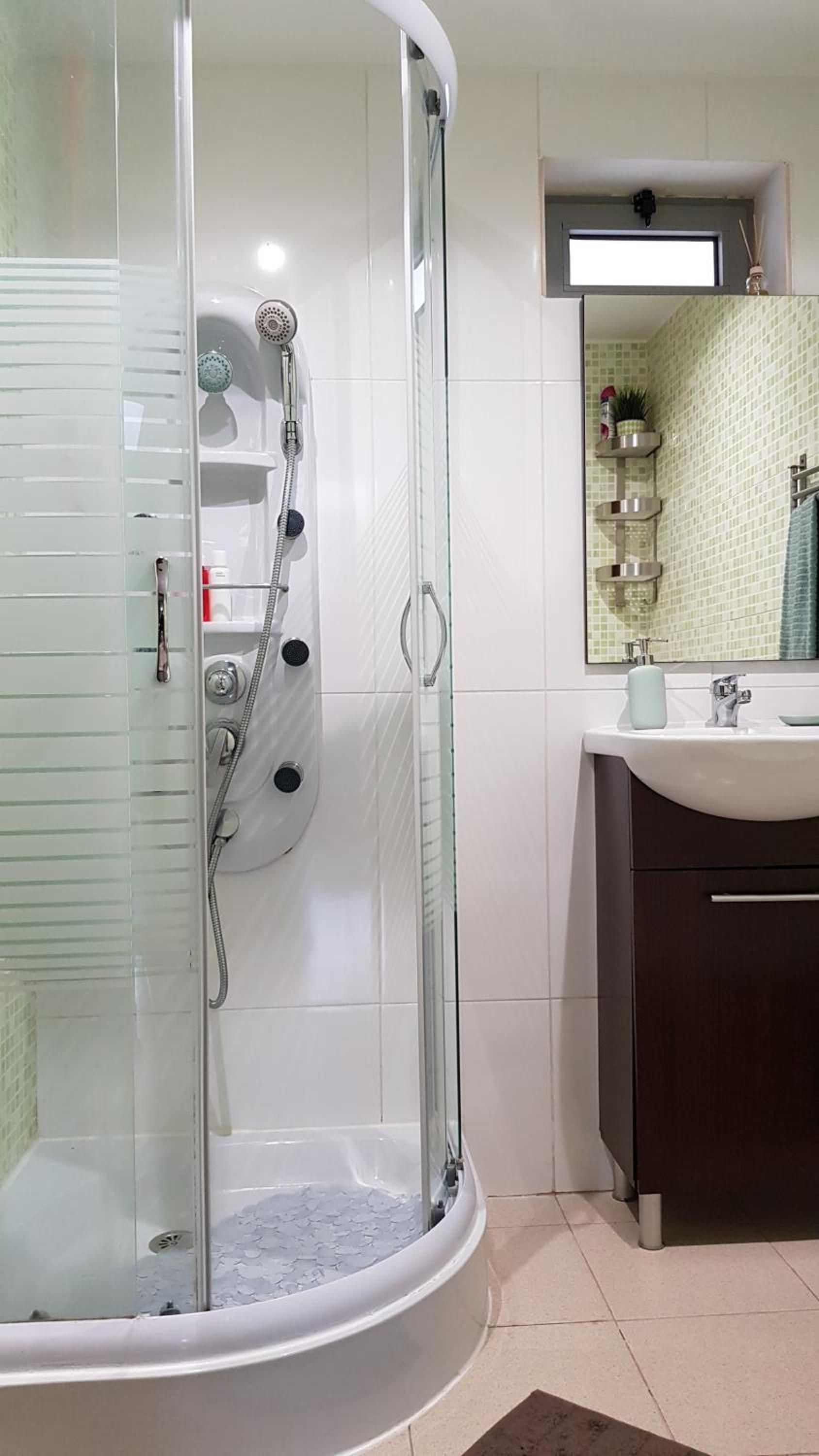 A modern bathroom with a glass-enclosed shower, a sink, and a mirror.