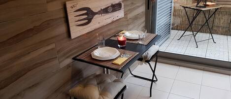 A dining area with a table set for two, a candle, and a wall-mounted wooden sign.