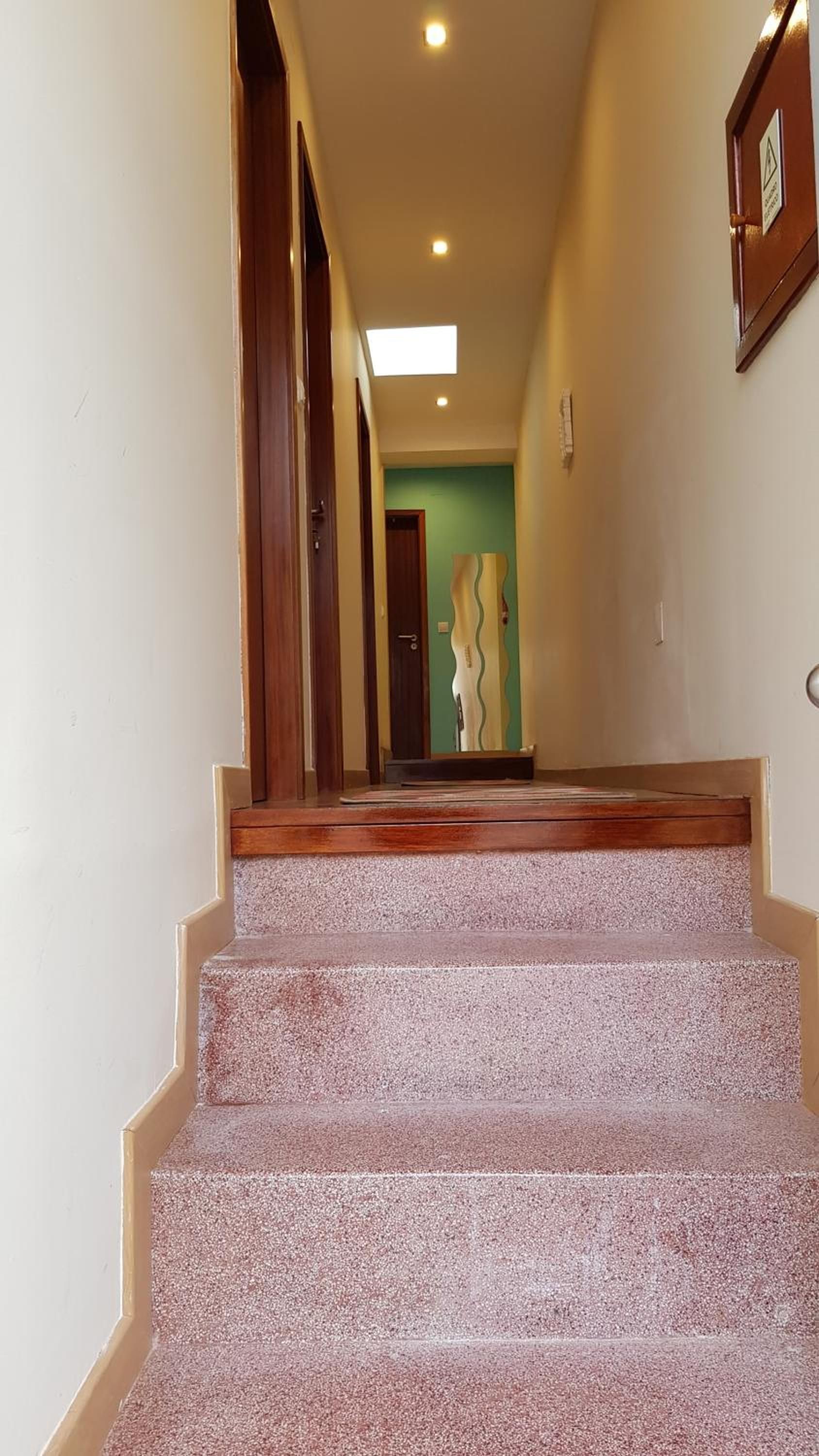 A staircase with a textured carpet leading to a room with a green wall and a decorative mirror.