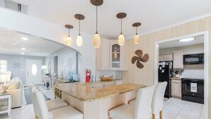 A modern kitchen with a central island, pendant lights, and a view into the dining area. - Manatee Oasis 4bed/3bath single family home with private pool & dockage located on the gulf side of Marathon (Marathon)