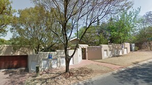A residential area with a gated entrance, a garage, and a tree-lined street. - Red Dot Lodge (Randburg)