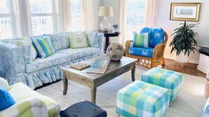 A living room with a blue patterned sofa, a wooden coffee table, and a blue armchair. - Designer Beach Retreat -Gulf views-Walk2Sand -Family & Dog Friendly (Galveston)