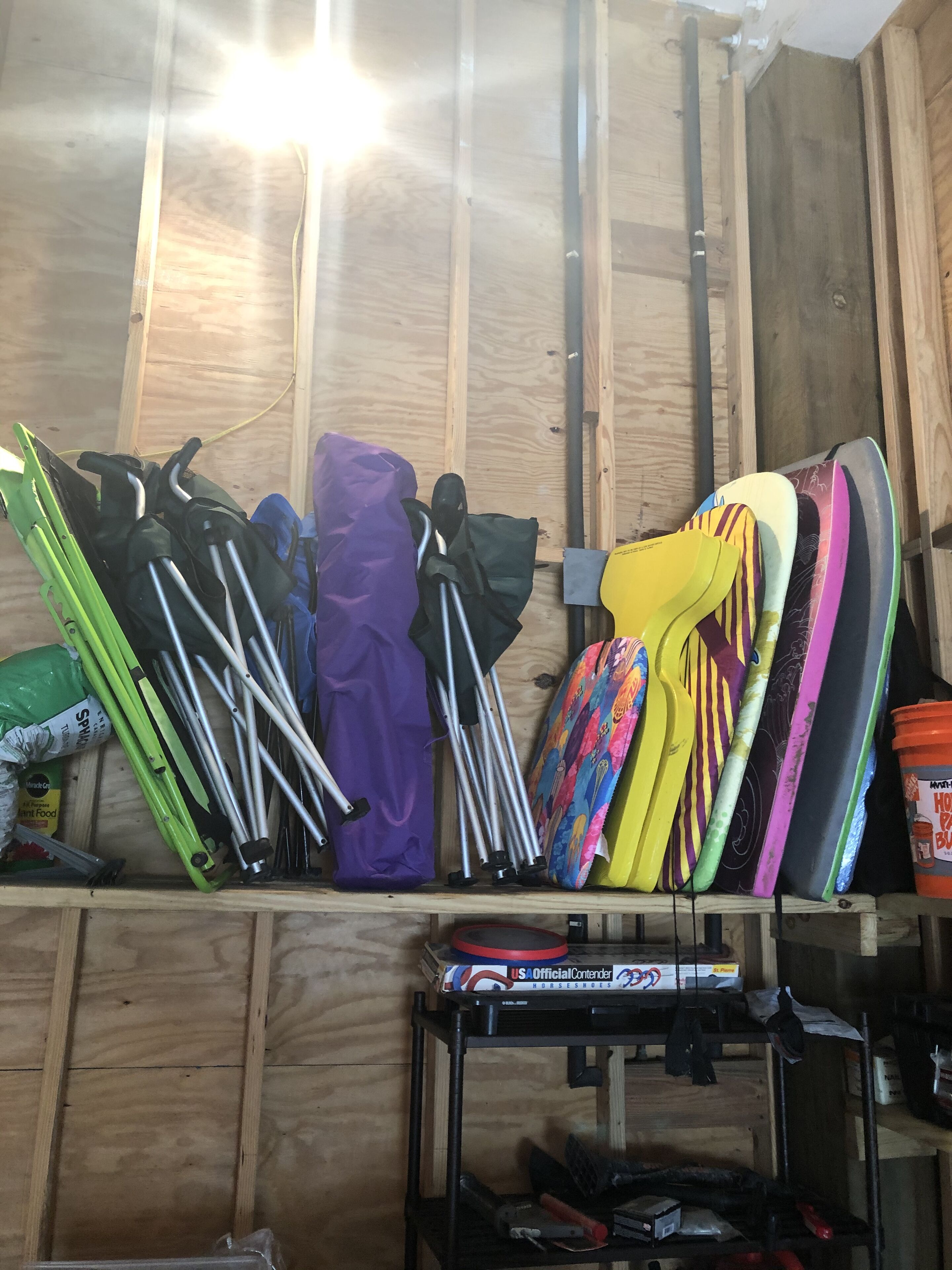Ein Lagerraum mit verschiedenen Gegenständen, darunter Ski, Snowboards und eine Kiste mit der Aufschrift 'USA Official Contender Horseshoes'.