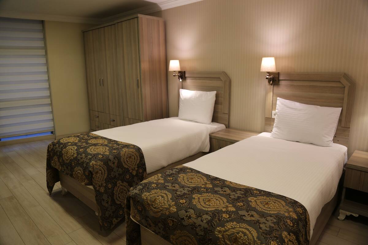 A hotel room with two beds, a wardrobe, and bedside lamps.
