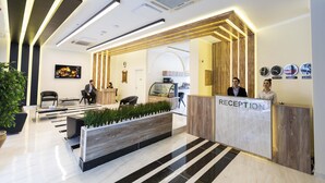 Un espace d’accueil moderne comprenant un comptoir de réception, des sièges et une présentation de plantes.