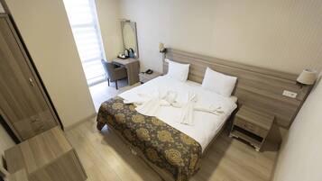 A hotel room with a bed, bedside table, nightstand, desk, chair, and a mirror.