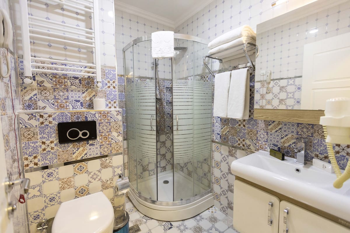 A bathroom with a glass-enclosed shower, a toilet, a sink, and patterned tiles.