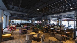 Un café spacieux avec de hauts plafonds, des planchers en bois et différents types de sièges, notamment des tables et des chaises.