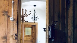 Une porte en bois avec un loquet métallique, un luminaire suspendu et un plancher en bois.