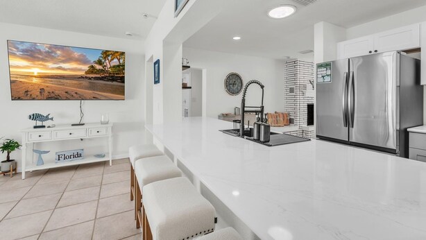 Una cocina moderna con una isla grande, electrodomésticos de acero inoxidable y vista a la playa.