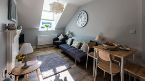 A cozy loft apartment with a loft bed, a gray sofa, a dining table, and a large wall clock. - 2 Sussex Place (Plymouth)