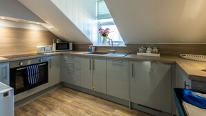 A modern kitchen with a built-in oven, microwave, and sink. - 2 Sussex Place (Plymouth)