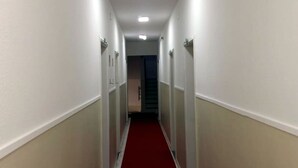 A narrow hallway with white walls and a red carpet, leading to a door at the end. - Hotel Amazônia Belém (Belém)