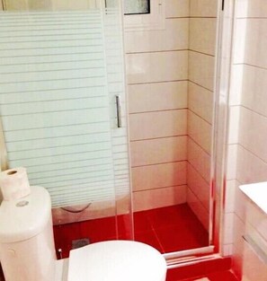 Un baño con inodoro, ducha y un rollo de papel higiénico.