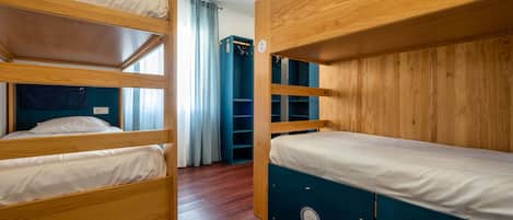 Una habitación con literas, un mueble de almacenamiento azul y un armario de madera.
