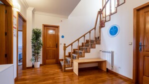 A wooden staircase with a bench at the bottom, a potted plant, and a blue sign on the wall. - InnEsposende Sports Hostel (Esposende)