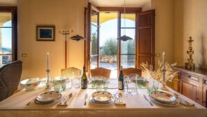 A dining table set with plates, glasses, and cutlery, with a view of the outdoors through open doors. - VILLA IL TORRIONE: Elegance and luxury home between Lucca and Florence with SPA (Pescia)