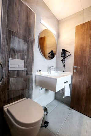 Une salle de bain moderne équipée de toilettes, d’un lavabo et d’un miroir.