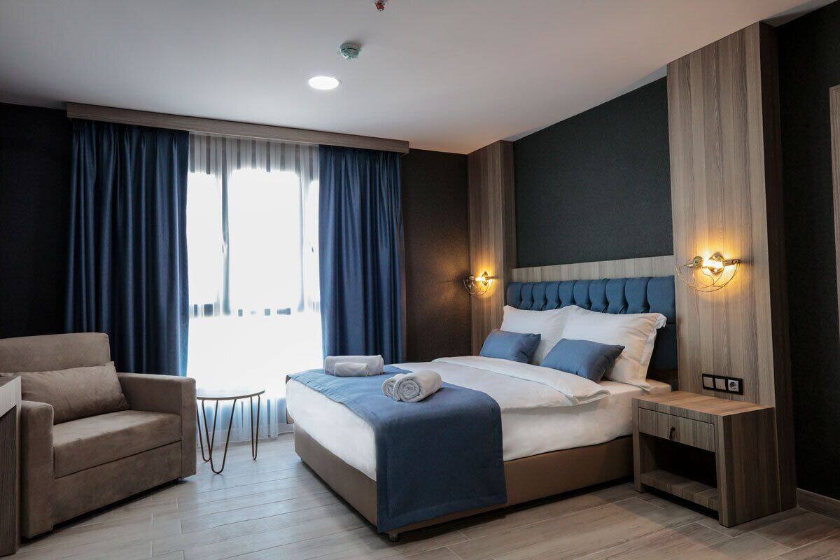 Una habitación de hotel moderna con una cama grande, un sofá, una mesita y una mesita de noche.